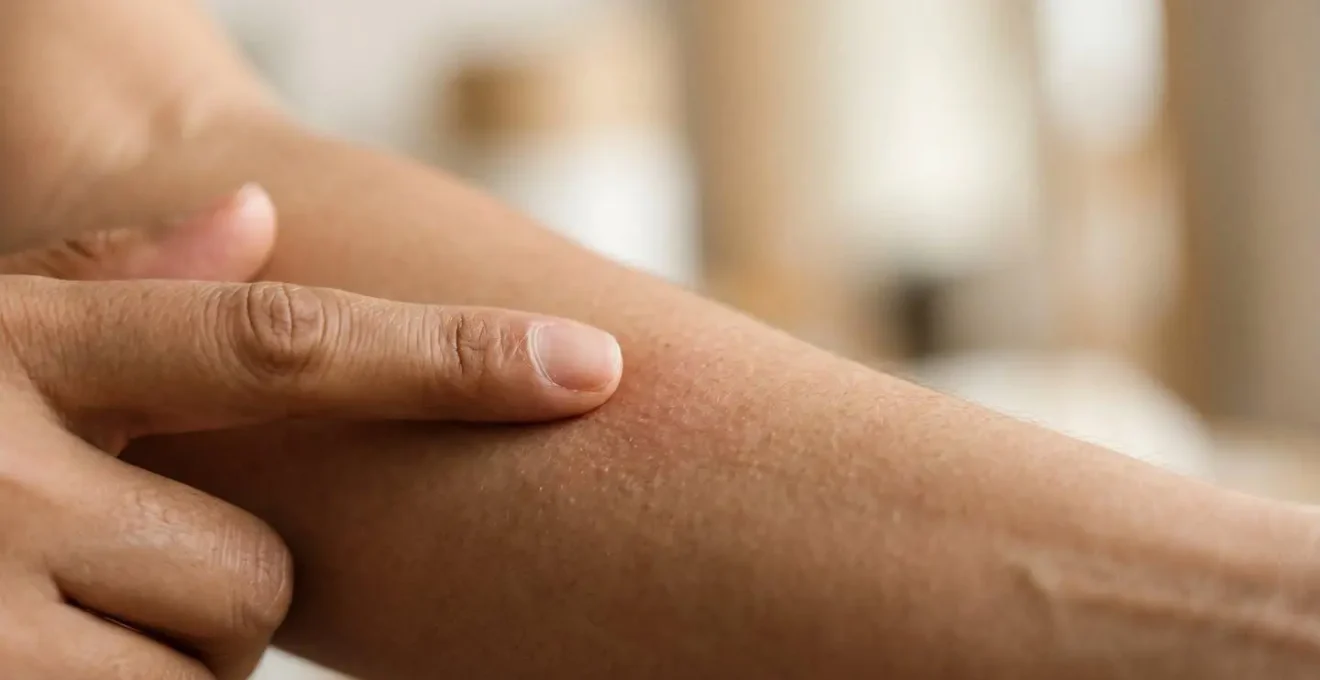 Primo piano di mano che indica lesione cutanea preoccupante per valutazione urgente